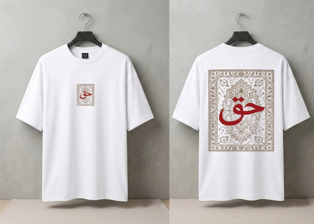 A white short-sleeve T-shirt shown from both front and back, hanging on a black hanger against a light gray wall. The front has a small square beige graphic with red Arabic calligraphy on the left chest.