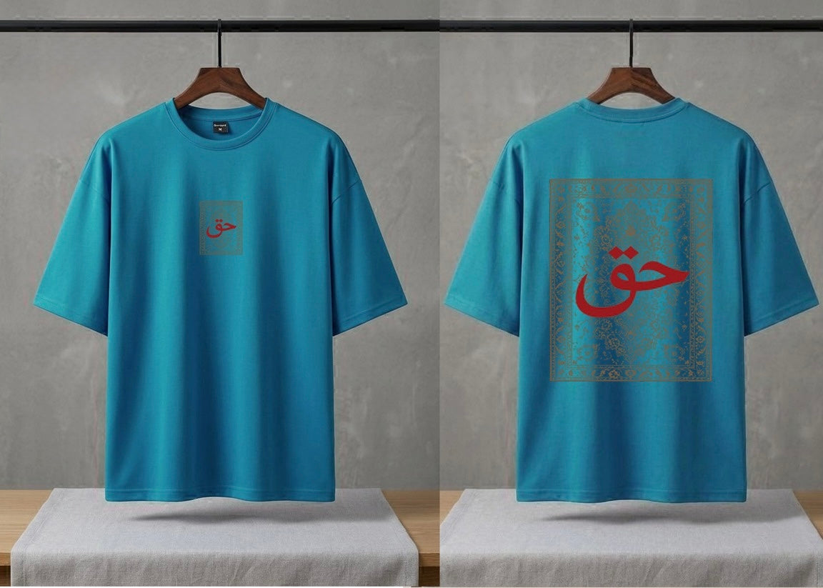 A bright turquoise blue short-sleeve t-shirt shown from both front and back views, hanging on wooden hangers against a textured gray wall. The front features a small square graphic on the left chest with red Arabic calligraphy.