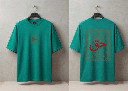 A teal green short-sleeve T-shirt shown from both front and back on black hangers against a textured light gray wall. The front has a small square chest graphic with red Arabic calligraphy.